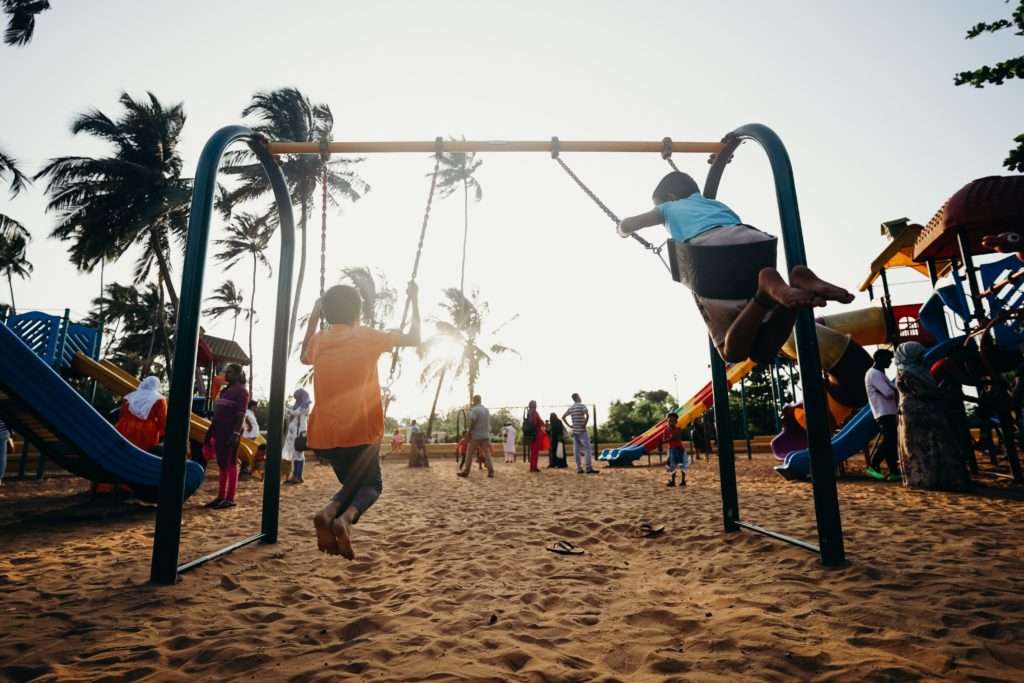 Enfants jouant sur une aire de jeux avec un sol en sable